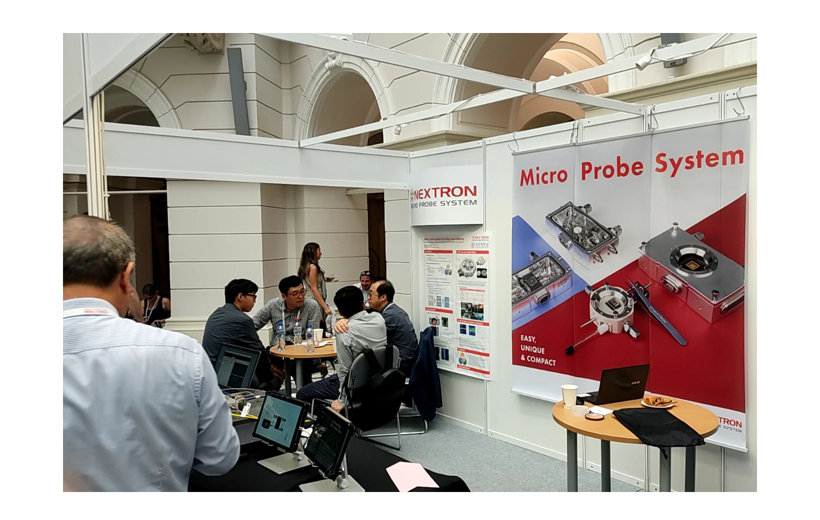 People discussing at Nextron's booth at 2023 E-MRS